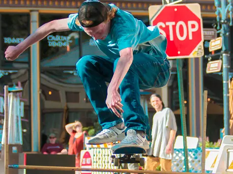 boy jumping over a limbo bar on a skateboard
