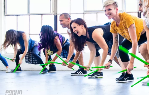 Girls using drumsticks and hitting ground while exercising